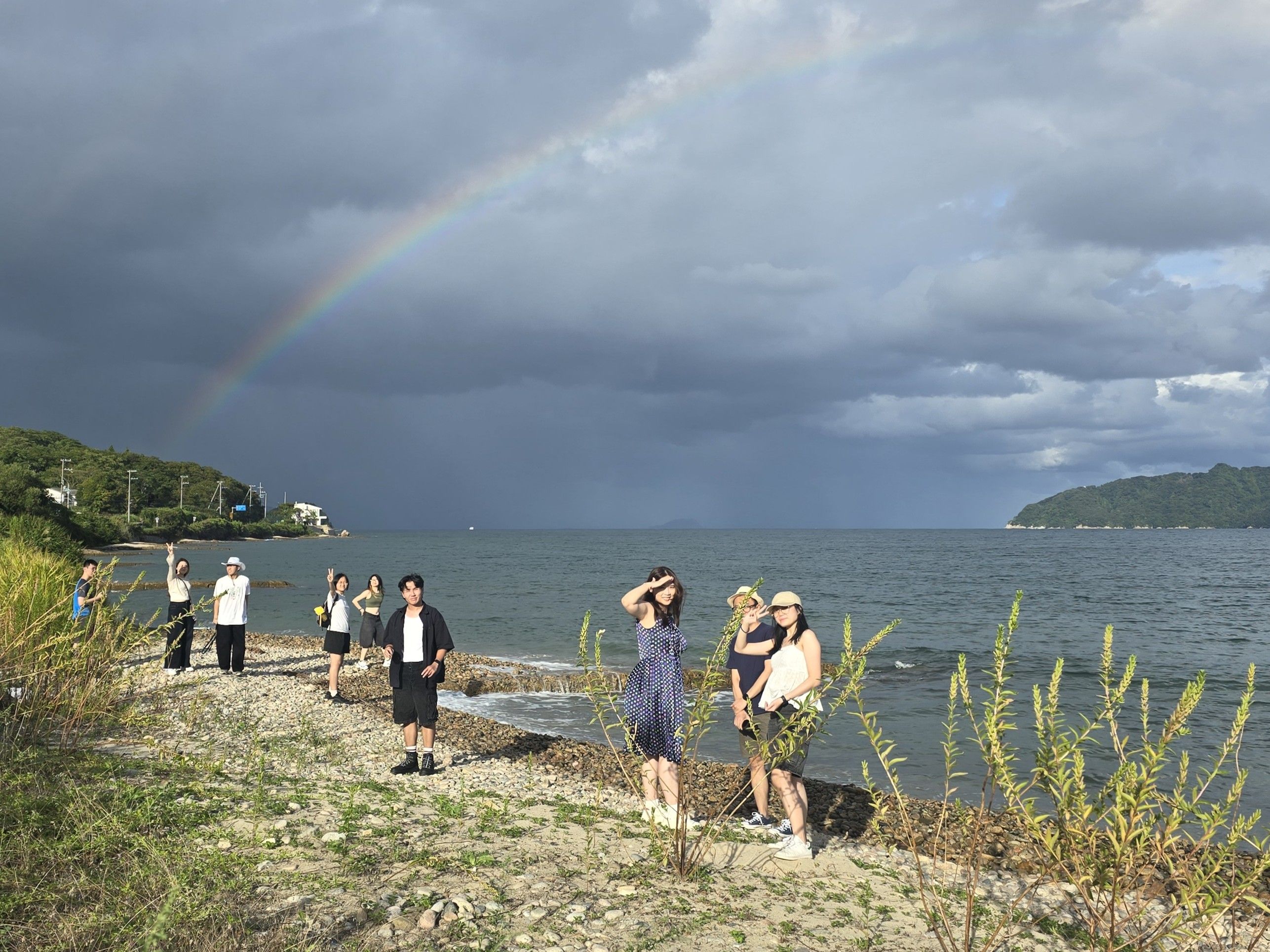 Group of us along a coast. There's a rainbow in the background.