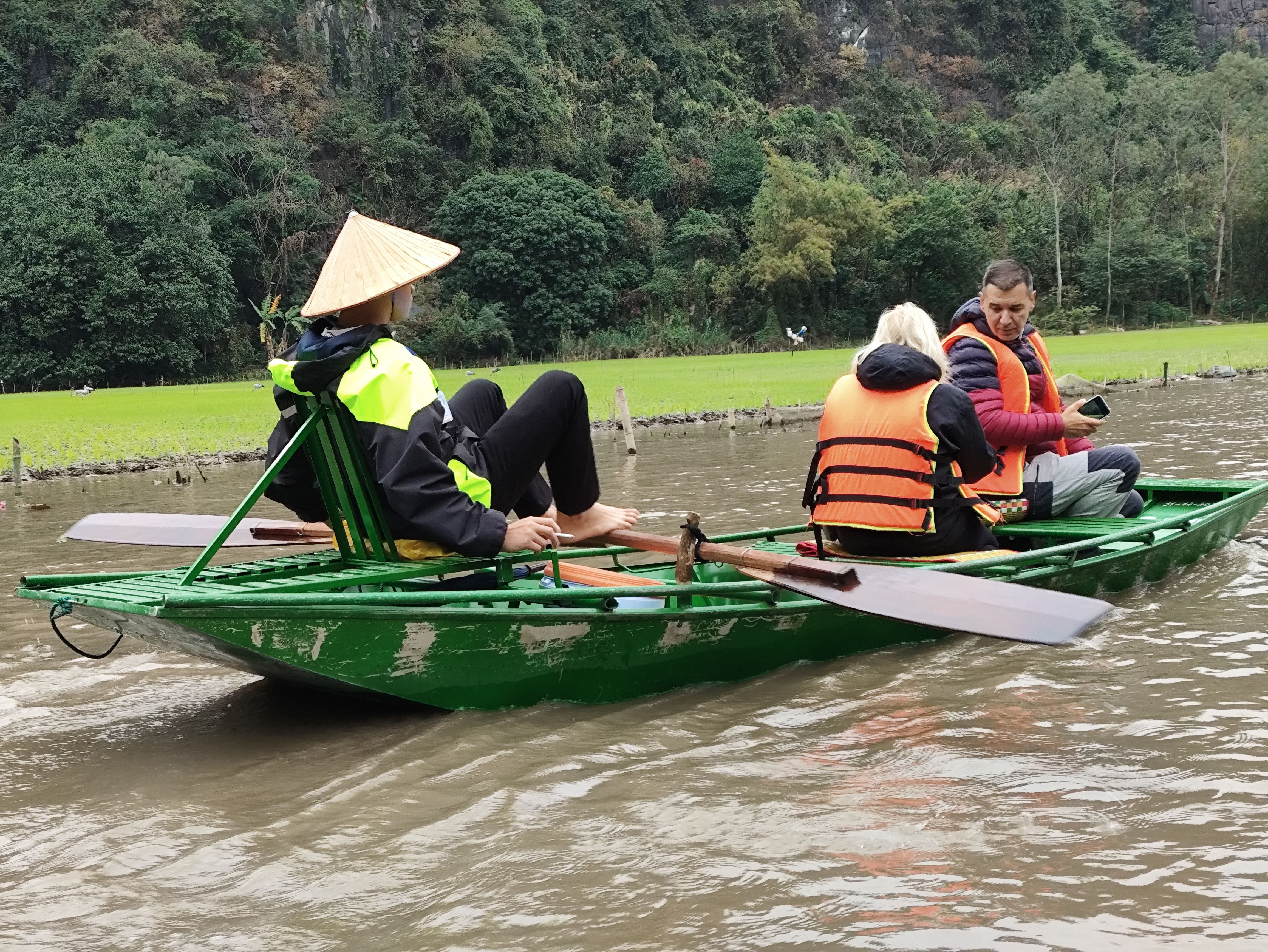 One of the boaters using his feet to row. His hand is free to hold a cigarette.