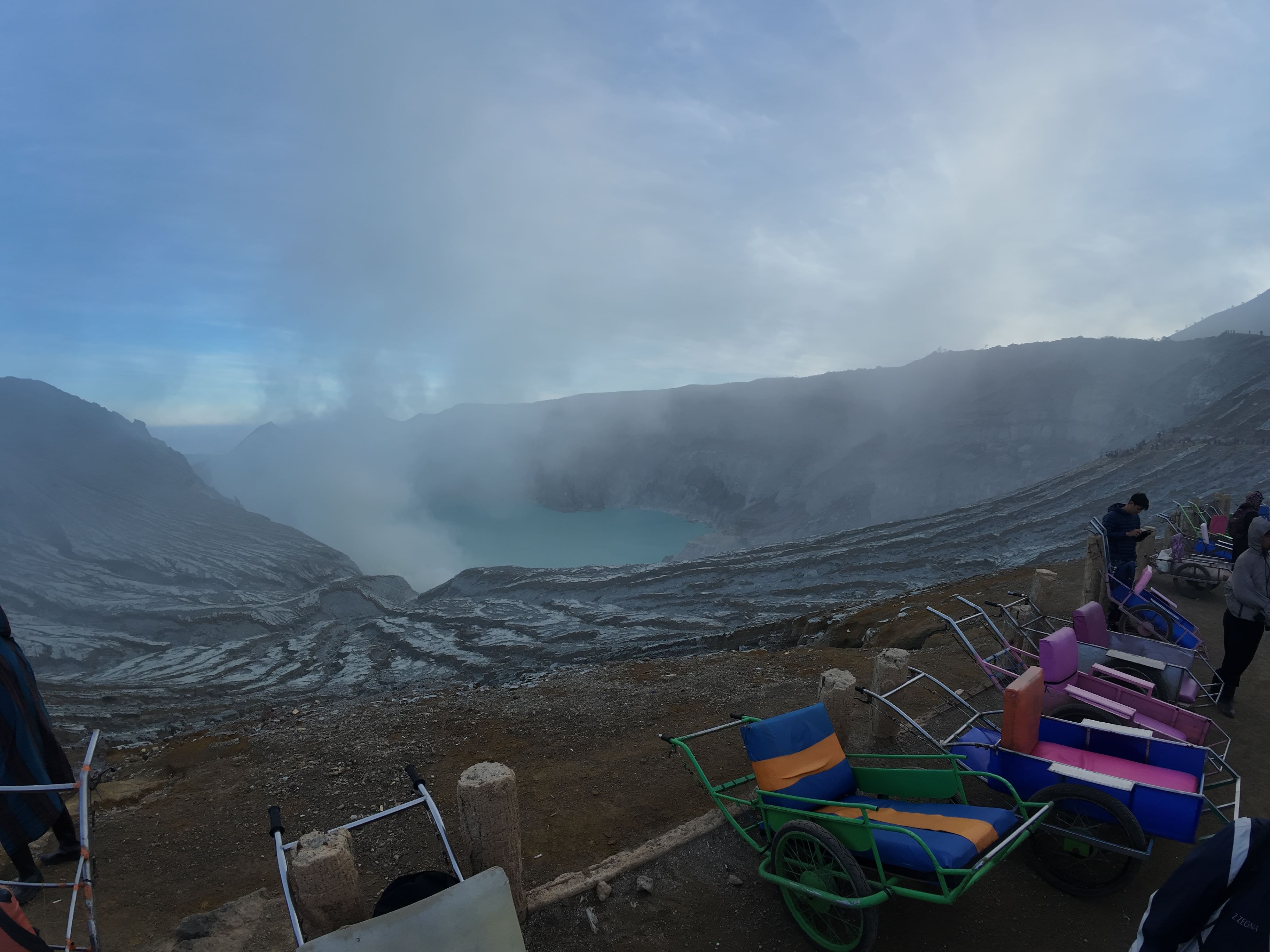 View of the lake and some smoke out of it. Some trolleys line the road